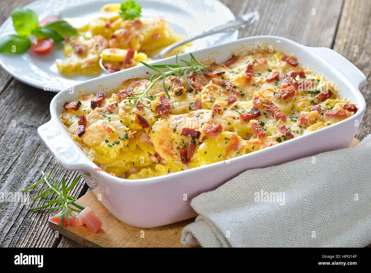 Hearty potato gratin with parmesan cheese, cream and delicious cured bacon from South Tyrol freshly served from the oven Stock Photo