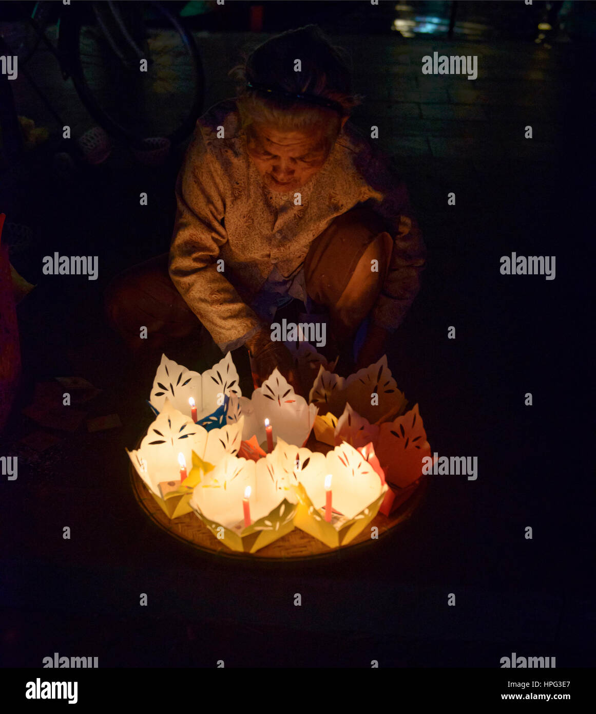 Old woman selling candles for full moon festival in old town Hoi An