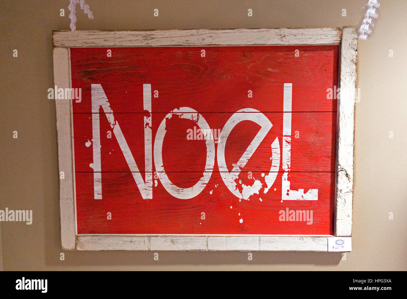 A roughly hewn red Christmas barnwood framed Noel sign with a rope hanger. Stock Photo