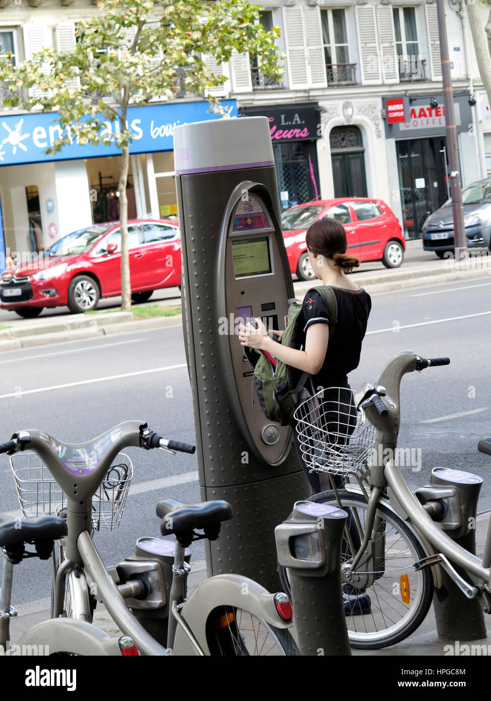 France, Paris, 3rd district. Boulevard Beaumarchais. Young woman renting a bike (Velib Stock