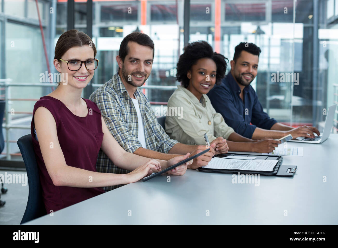 Portrait of smiling business executives sitting together in meeting at ...