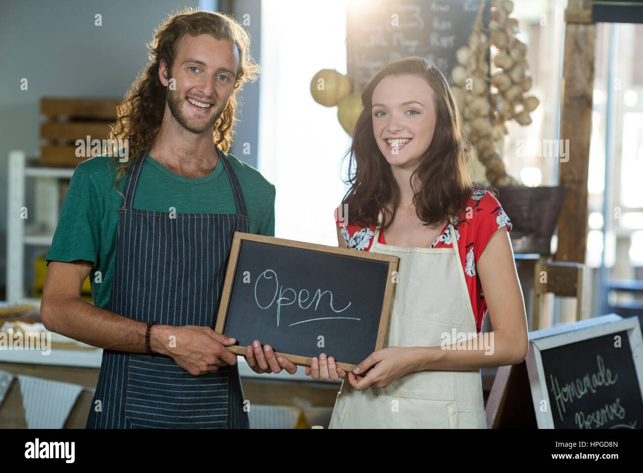 Shop assistants holding open sign board at grocery shop Stock Photo
