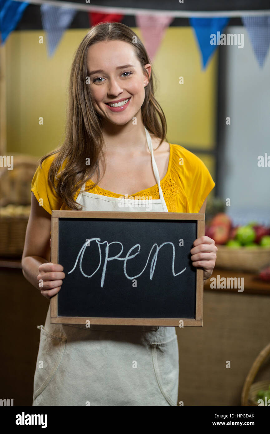 female worker holding a board with open sign at grocery store Stock Photo