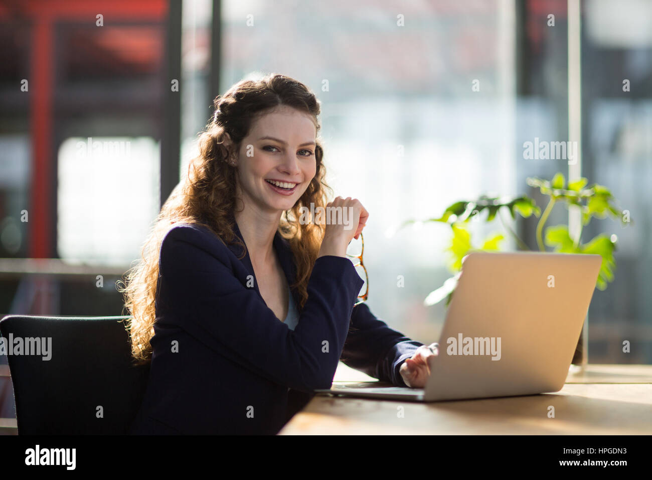 Portrait of smiling female business executive sitting in office with ...