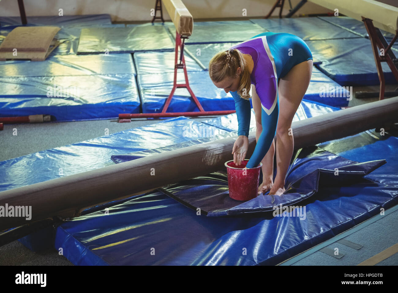 Female gymnast applying chalk powder on her hands before practicing in