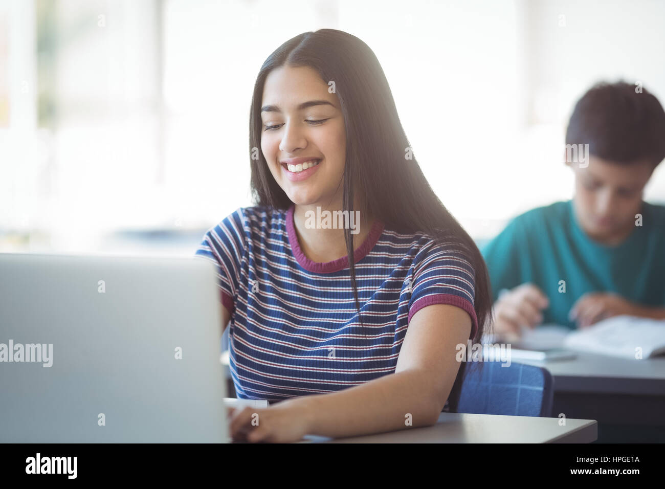 Happy schoolgirl using laptop in classroom at school Stock Photo - Alamy