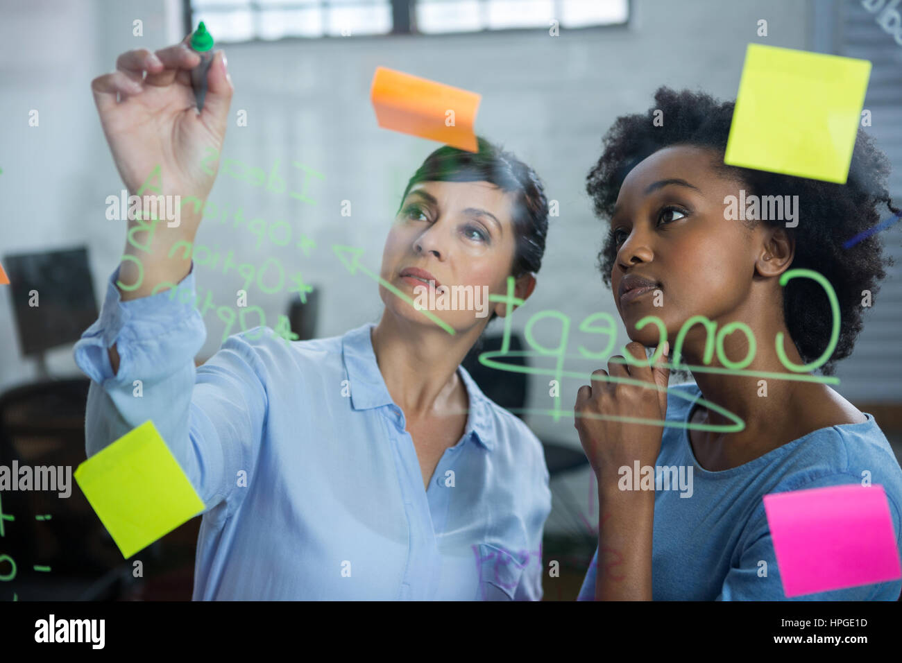 Female graphic designers writing on glass with marker Stock Photo - Alamy