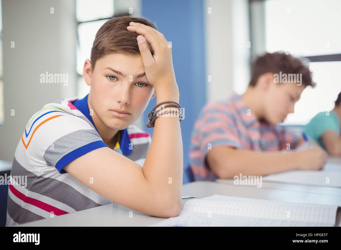 Portrait of schoolboy sitting at desk in classroom Stock Photo - Alamy