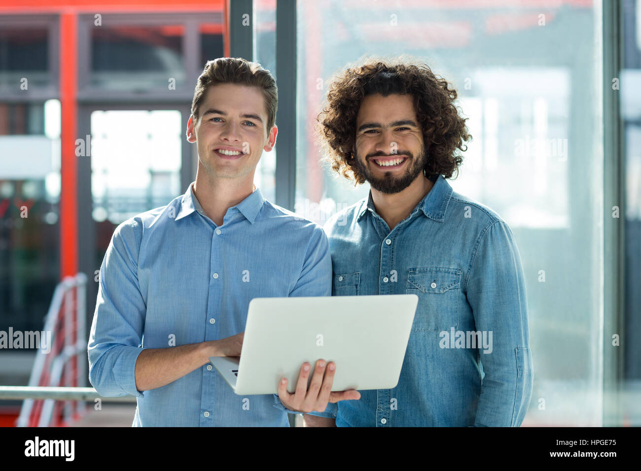 Portrait of smiling business executives using laptop in office Stock ...