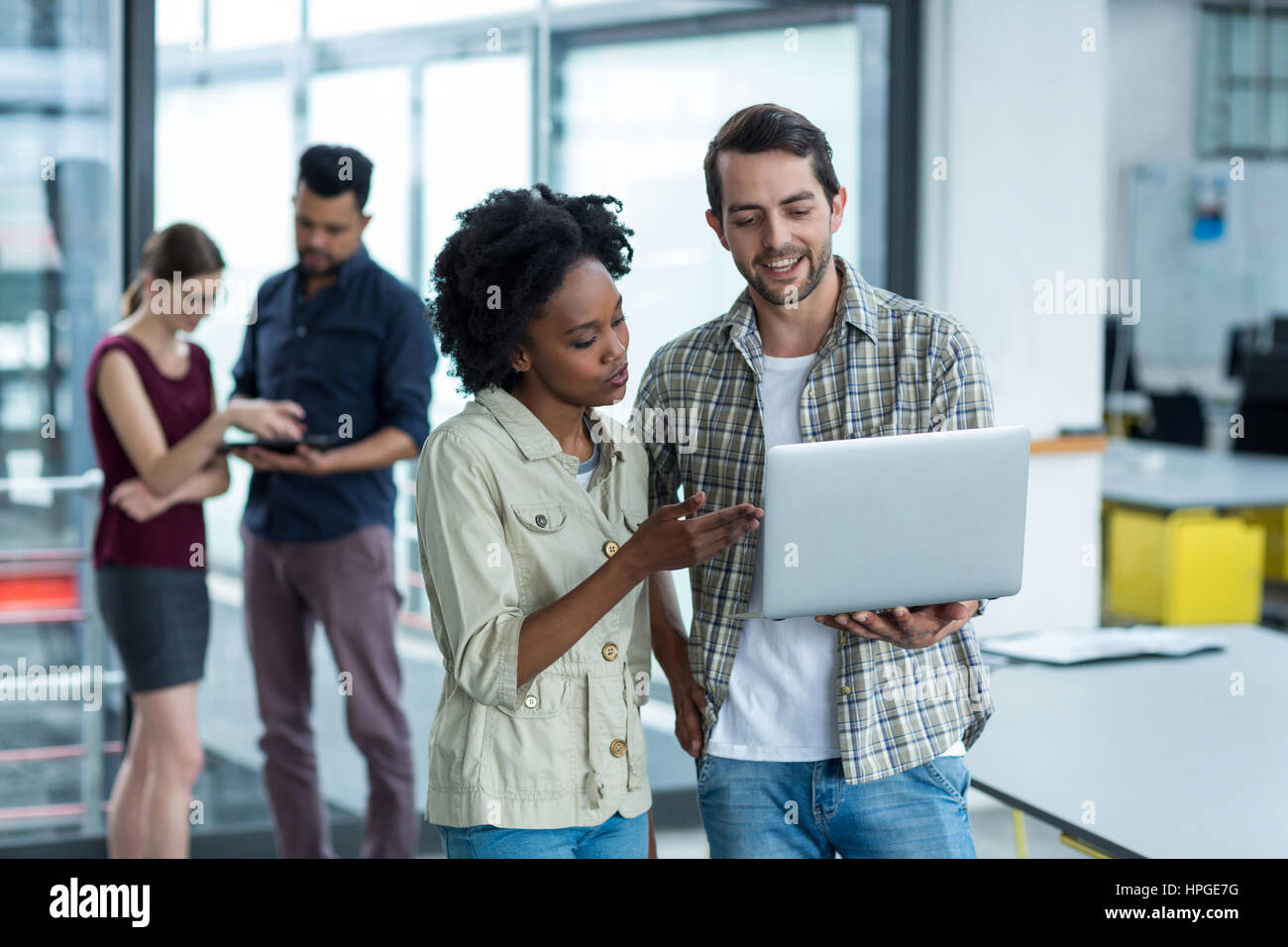Smiling business executives discussing over laptop in office Stock ...