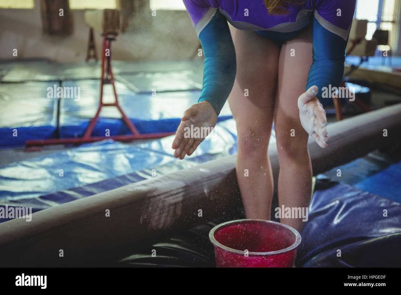 Midsection of a female gymnast applying chalk powder on her hands
