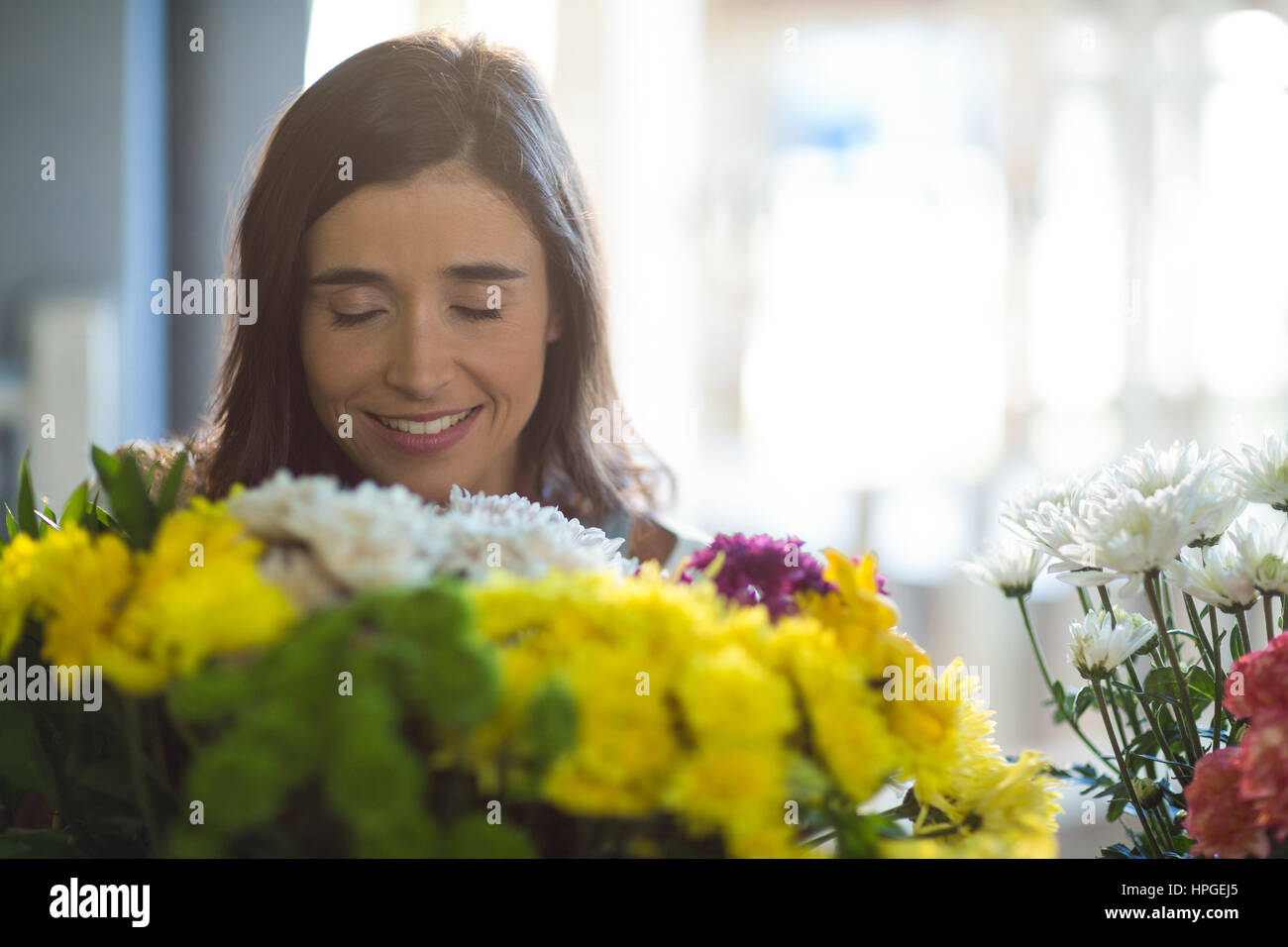 Smiling woman holding a bouquet with eyes closed in the florist shop ...