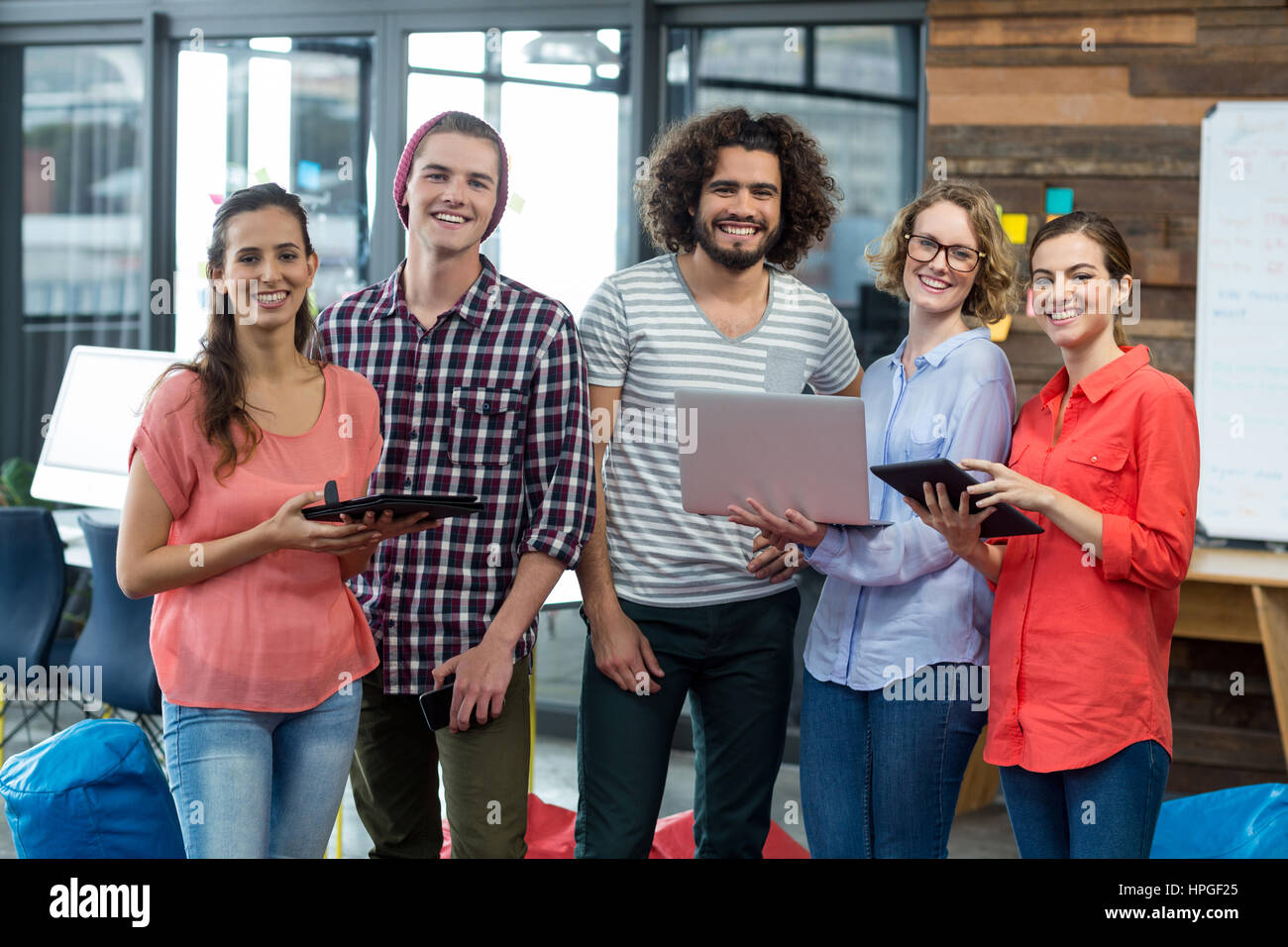 Portrait of smiling business executives standing in office with digital ...