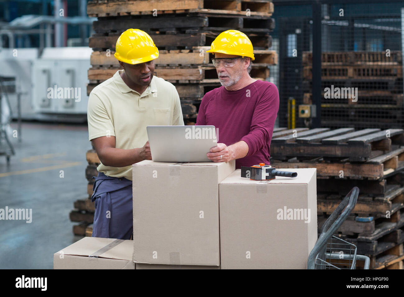 Two factory workers working together on laptop in drinks production