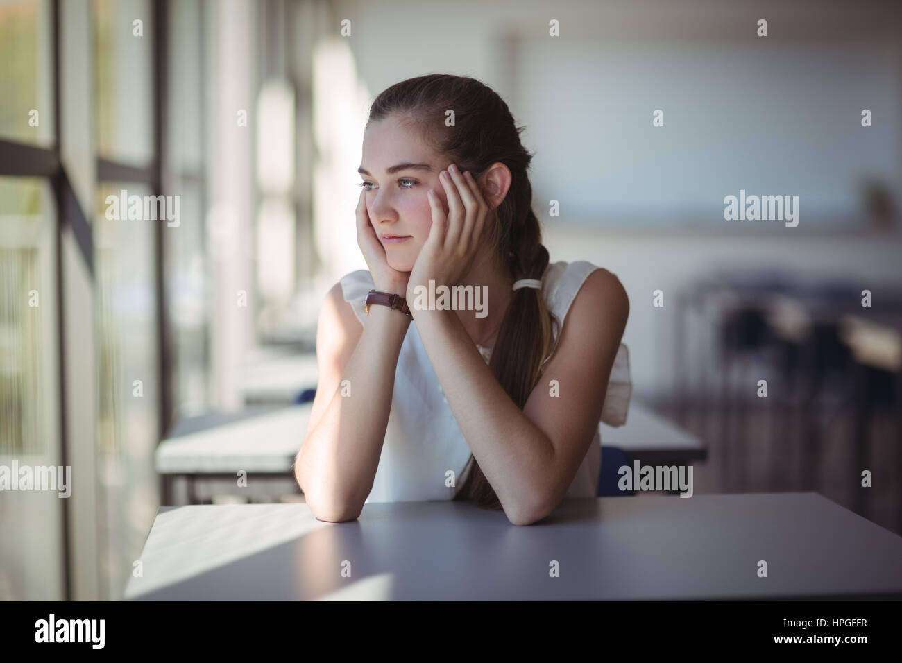 Thoughtful schoolgirl sitting in classroom at school Stock Photo - Alamy