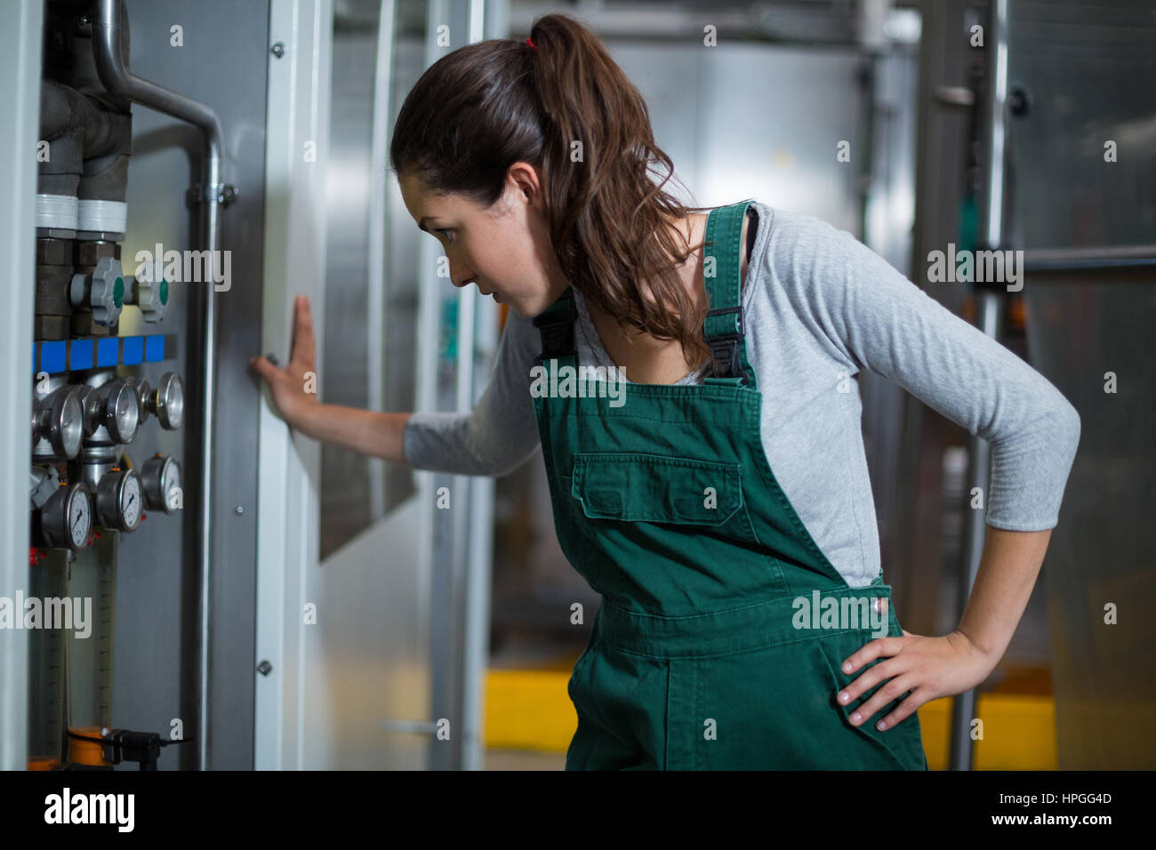 Female factory worker inspecting machinery at drinks production factory Stock Photo