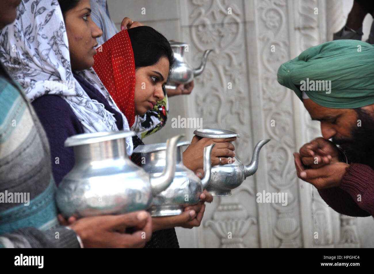 Pilgrims drinking holy water, Bangla Sahib Gurudwara, Sikh temple is located near the main Cannaught Place in New Delhi  (Photo © Saji Maramon) Stock Photo