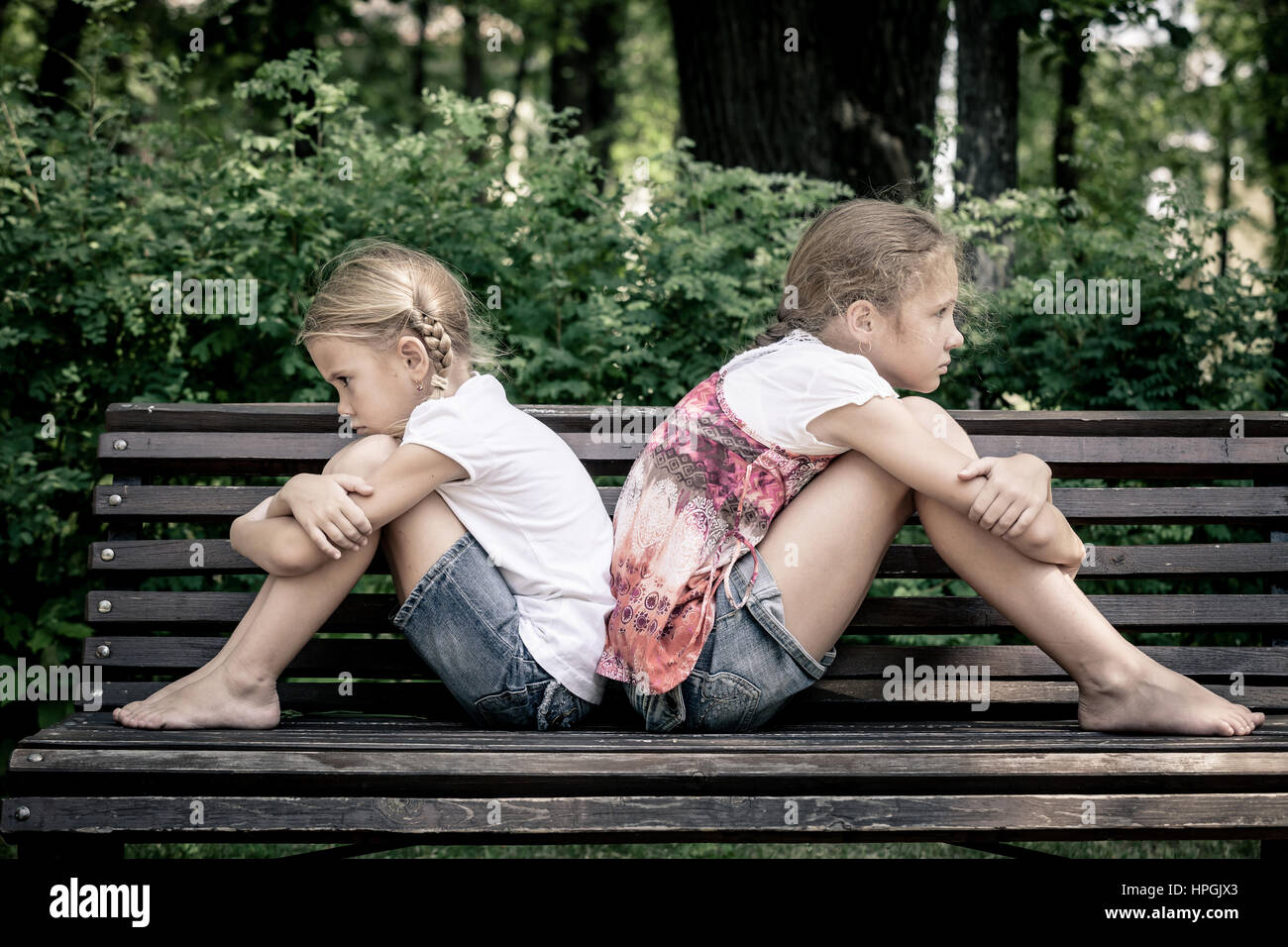 two sad sister sitting on the bench in park at the day time Stock Photo ...