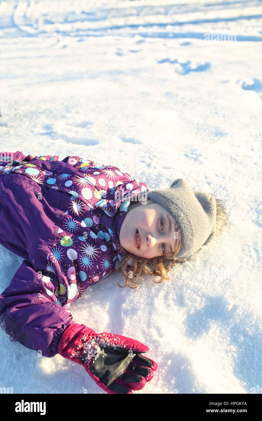 cheerful young girl lies on the snow Stock Photo
