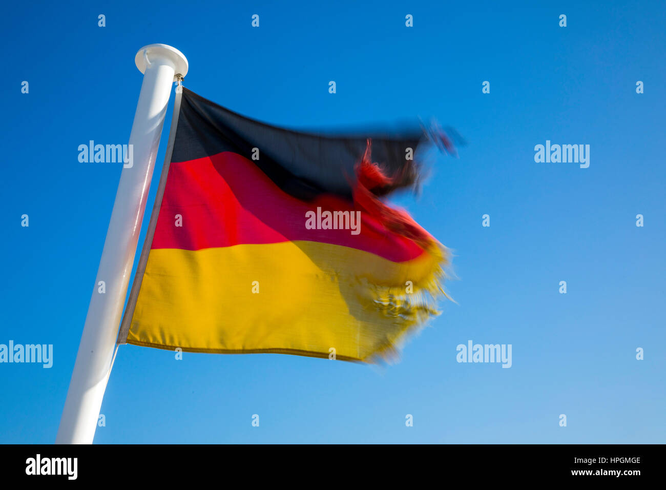 Flag of the Federal Republic of Germany, fluttering in the wind, is frayed, torn, Stock Photo