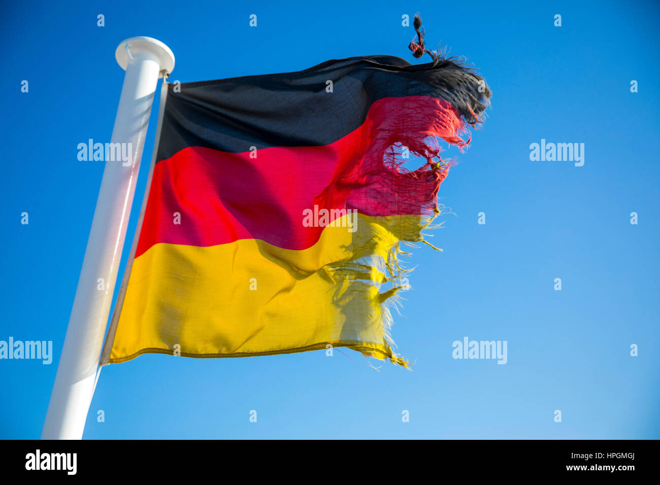 Flag of the Federal Republic of Germany, fluttering in the wind, is frayed, torn, Stock Photo