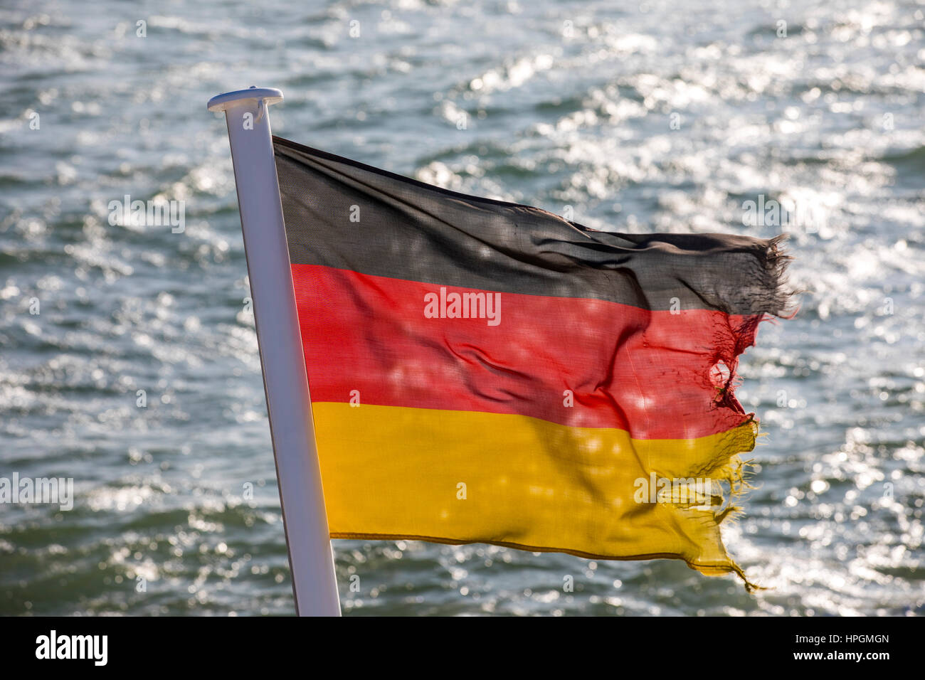 Flag of the Federal Republic of Germany, fluttering in the wind, is frayed, torn, Stock Photo