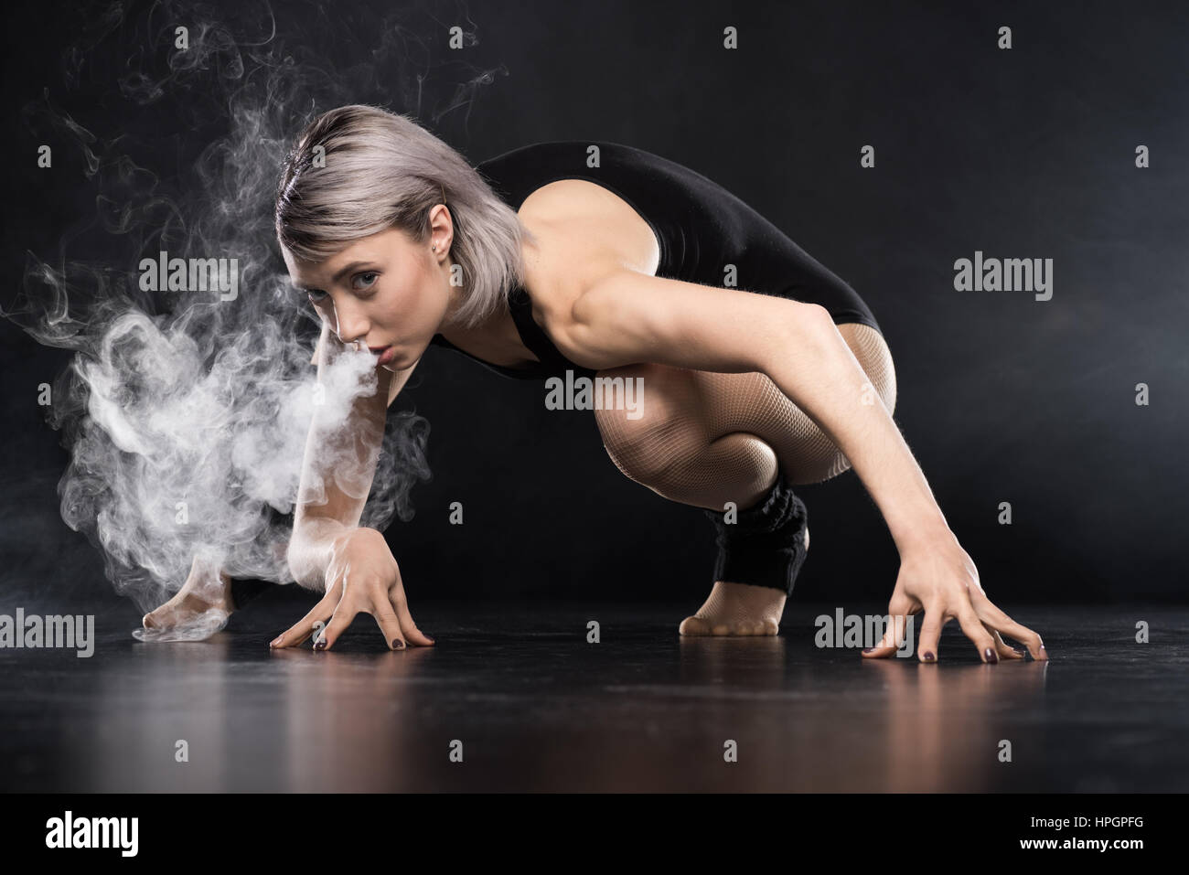 woman in bodysuit exhaling smoke Stock Photo