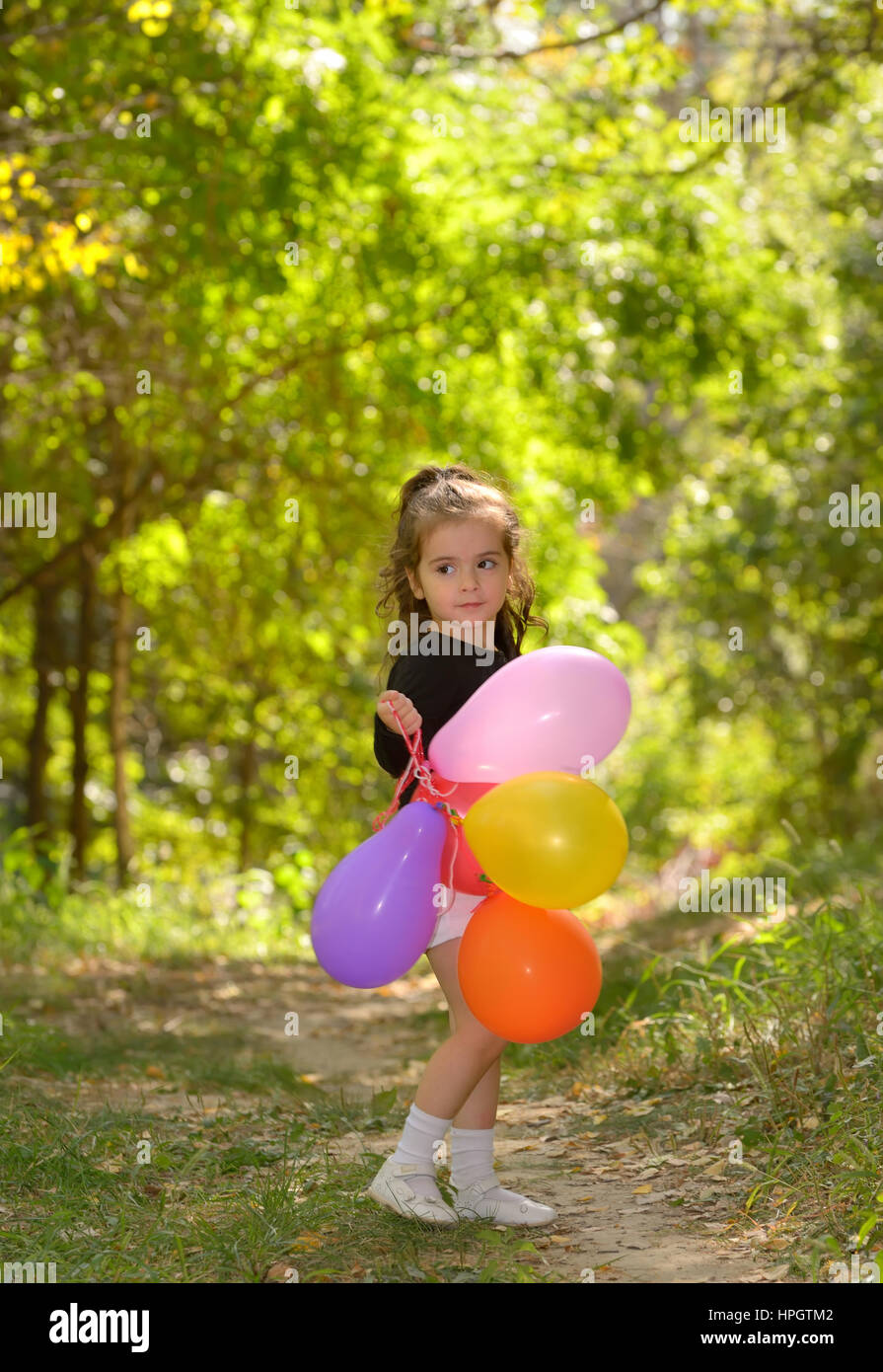 Little girl with colorful balloons in forest Stock Photo - Alamy