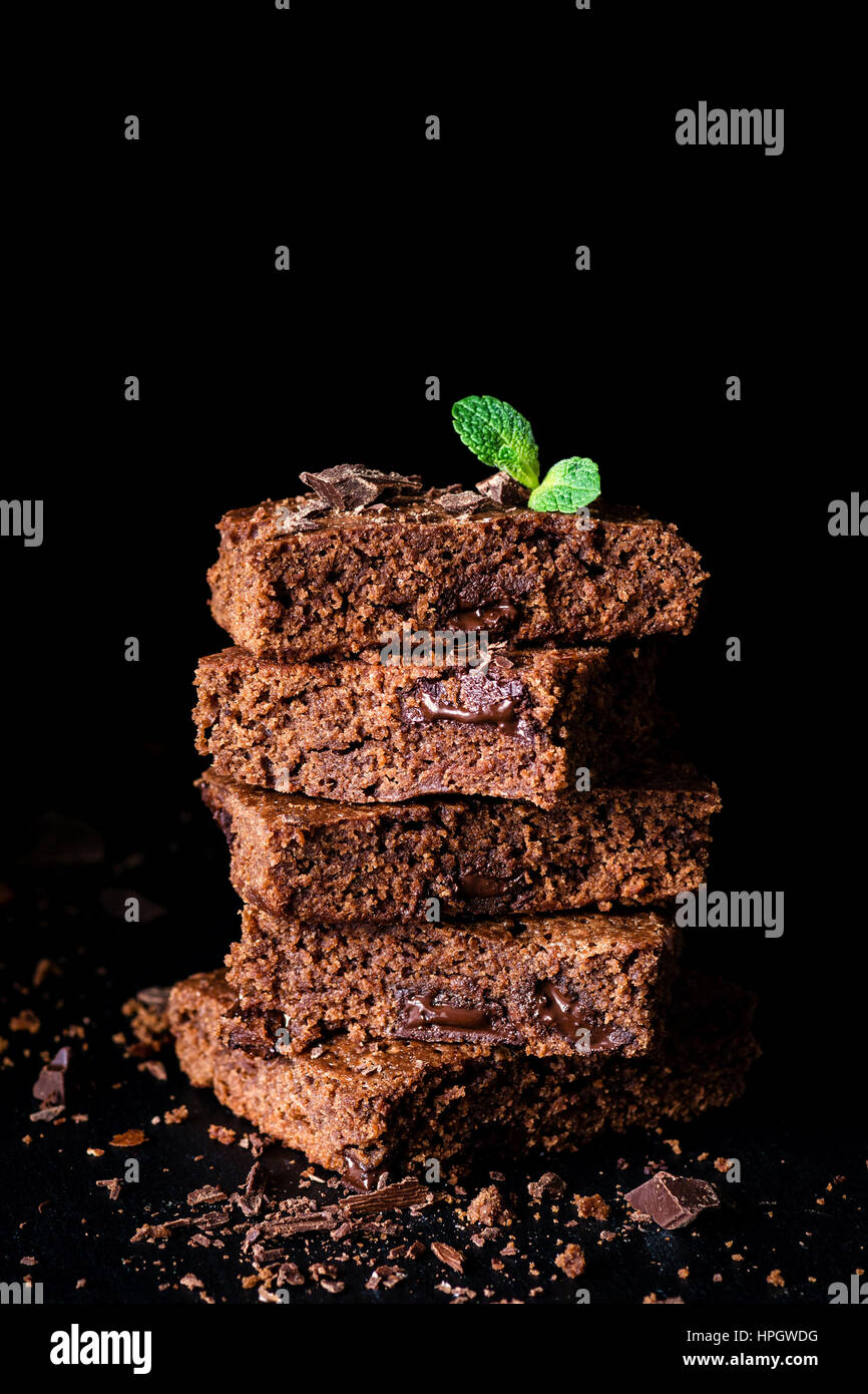 Stack of brownies with dark chocolate over black background, closeup view, vertical composition Stock Photo