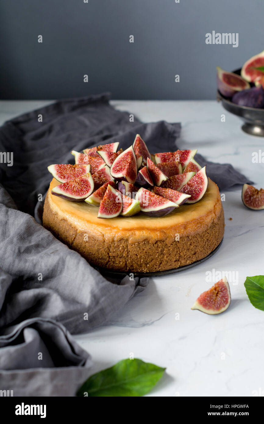 Whole cheesecake decorated with fresh figs on a marble table. Vertical view, copy space for text Stock Photo