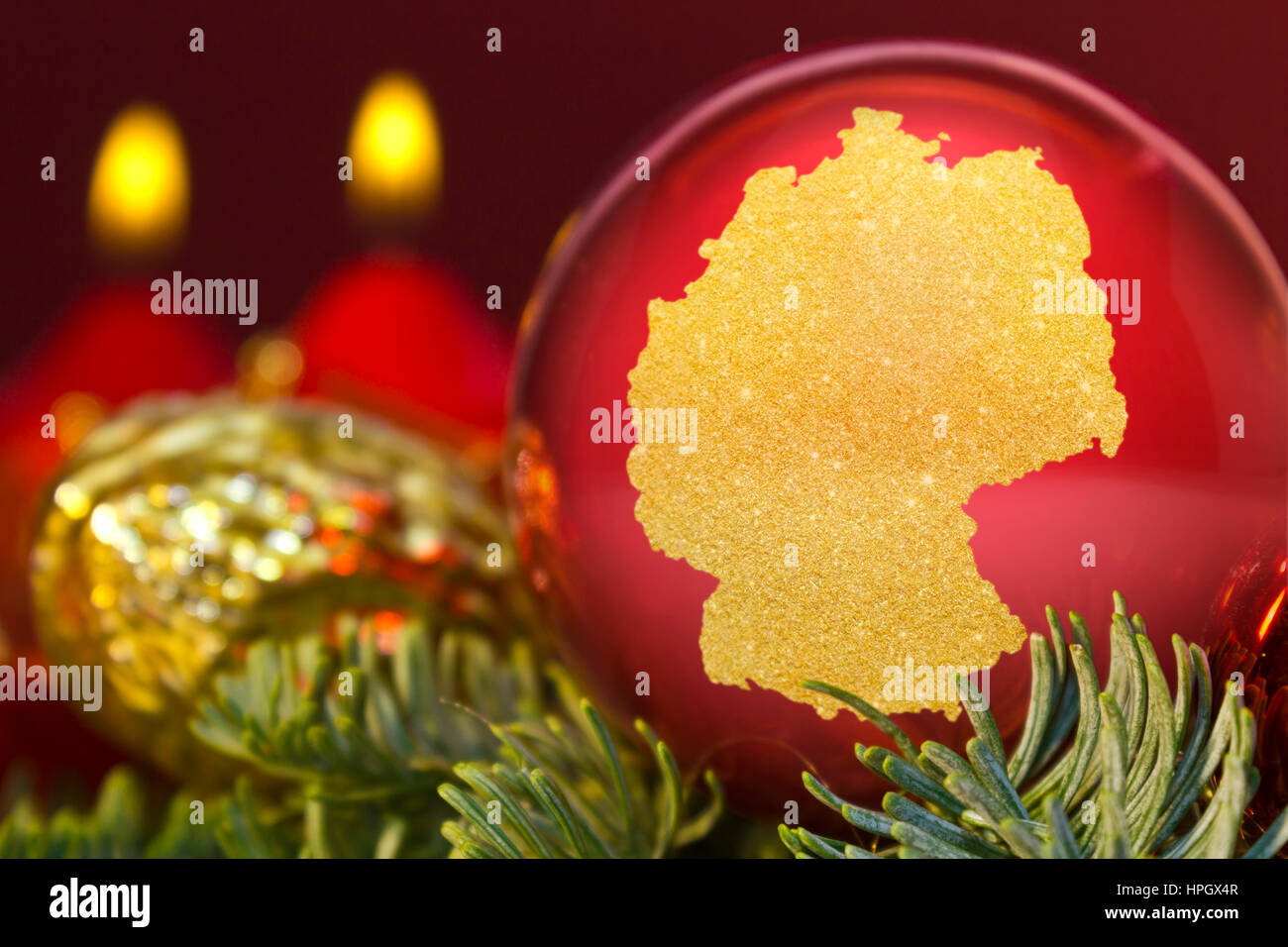 A glossy red bauble with the golden shape of Germany.(series Stock