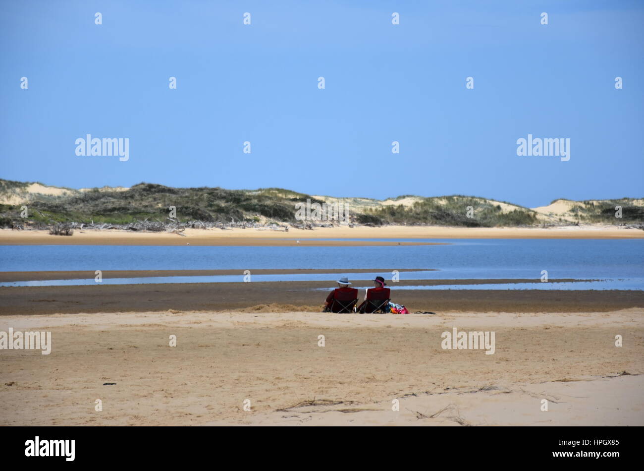 Old couple resting on the beach. View of coastline of Marlo Recreational Reserve in summer, Marlo in Victoria, Australia. The Snowy River flows into t Stock Photo