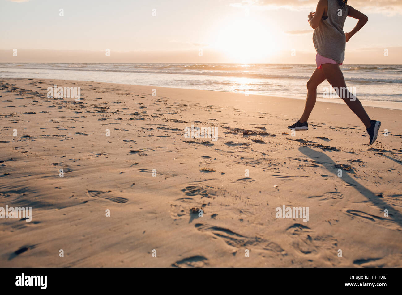 Outdoor shot of female exercising on the beach. Woman on morning run, focus on feet. Stock Photo