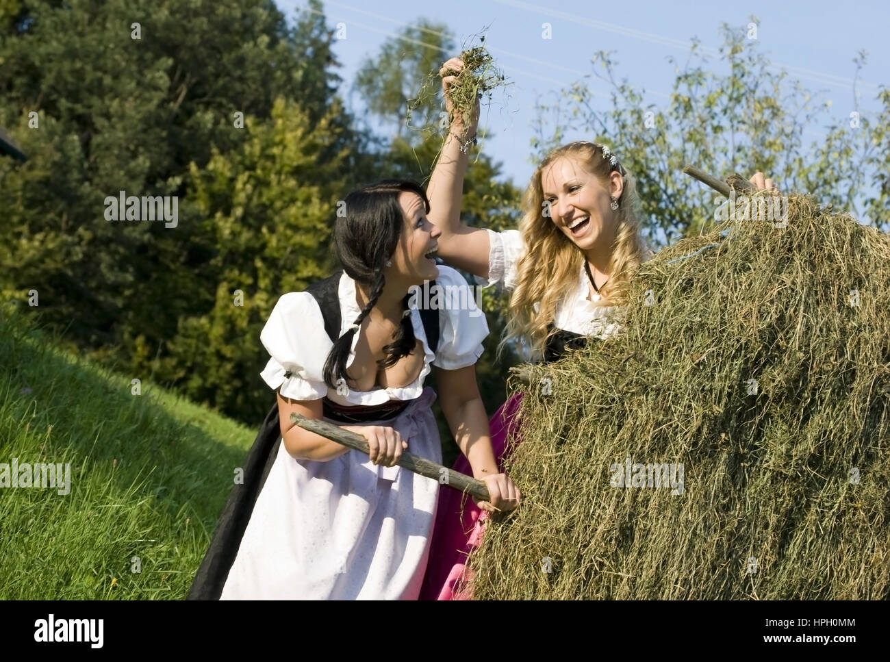 Model released , Zwei junge Frauen im Dirndl bei der Heuarbeit - women in dirndl do hay harvest Stock Photo