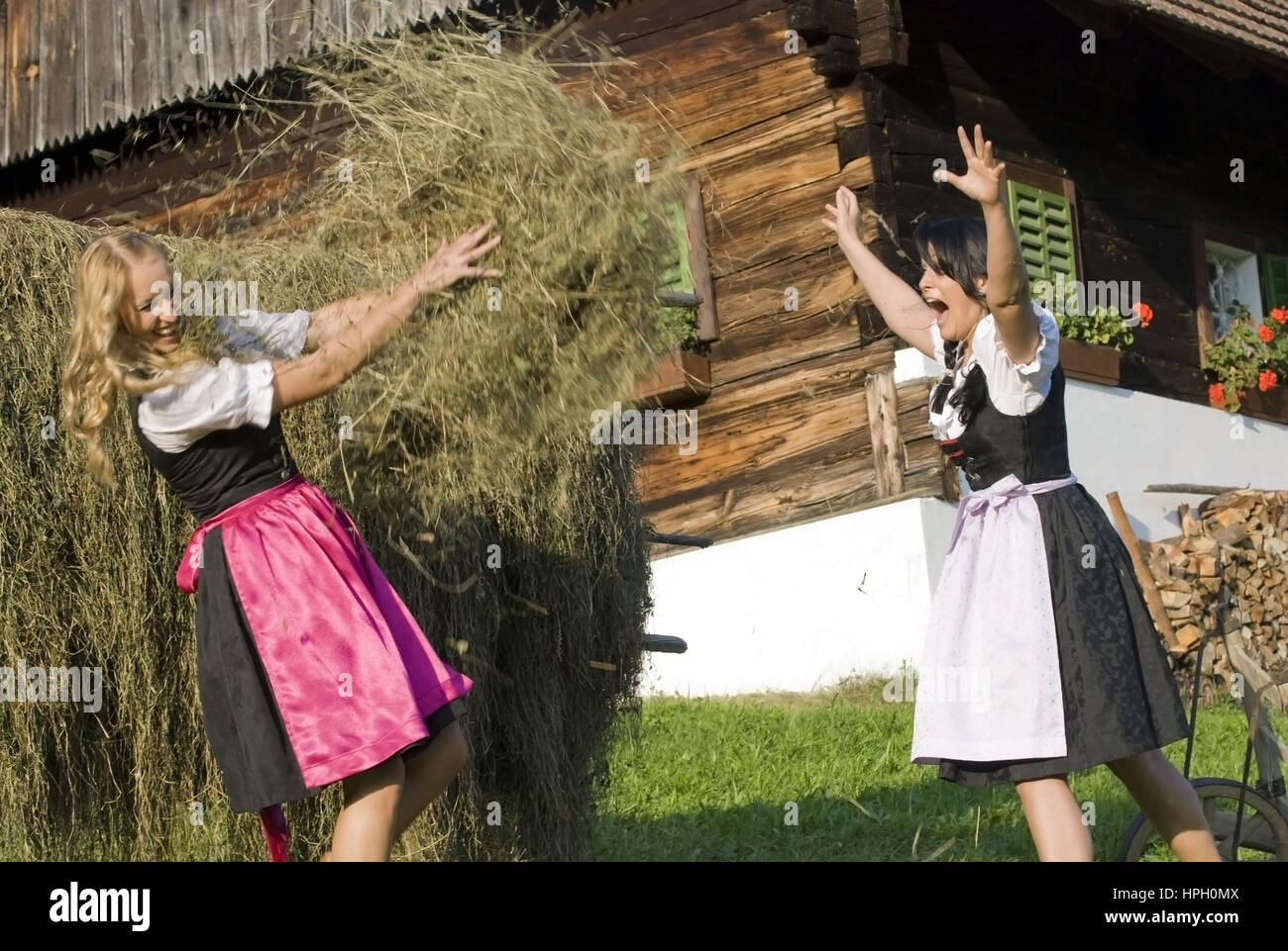 Model released , Zwei junge Frauen im Dirndl bei der Heuarbeit - women in dirndl do hay harvest Stock Photo