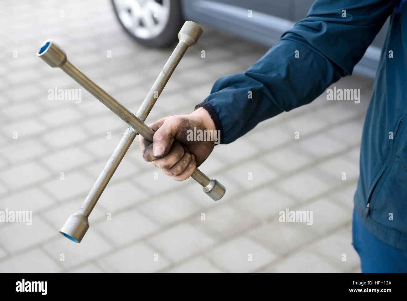 Model released , Mechaniker mit Kreuzschluessel in der Hand - mechanic with wheelbrace in hand Stock Photo