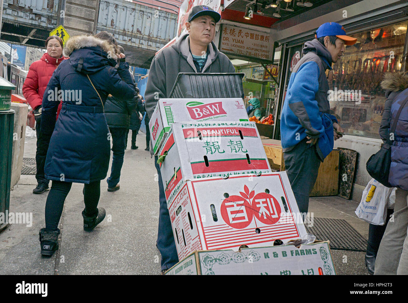 An Asian American worker moving boxes on Main Street in Chinatown, Flushing, Queens, New York City. Stock Photo