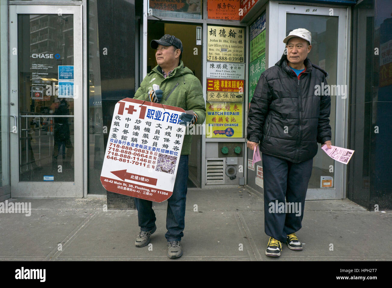 Unskilled Chinese American workers outdoors on a winter afternoon in Chinatown, Flushing, New York City Stock Photo