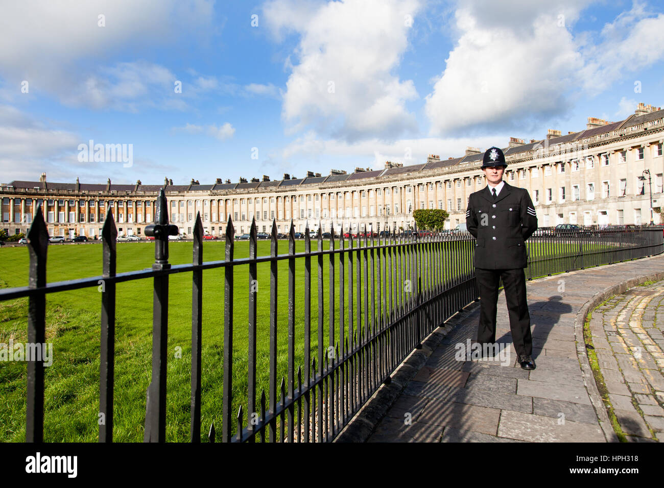 An English policeman, Bobby or Copper, standing Royal Crescent In Bath England. He's wearing a formal tunic and custodian helmet Stock Photo