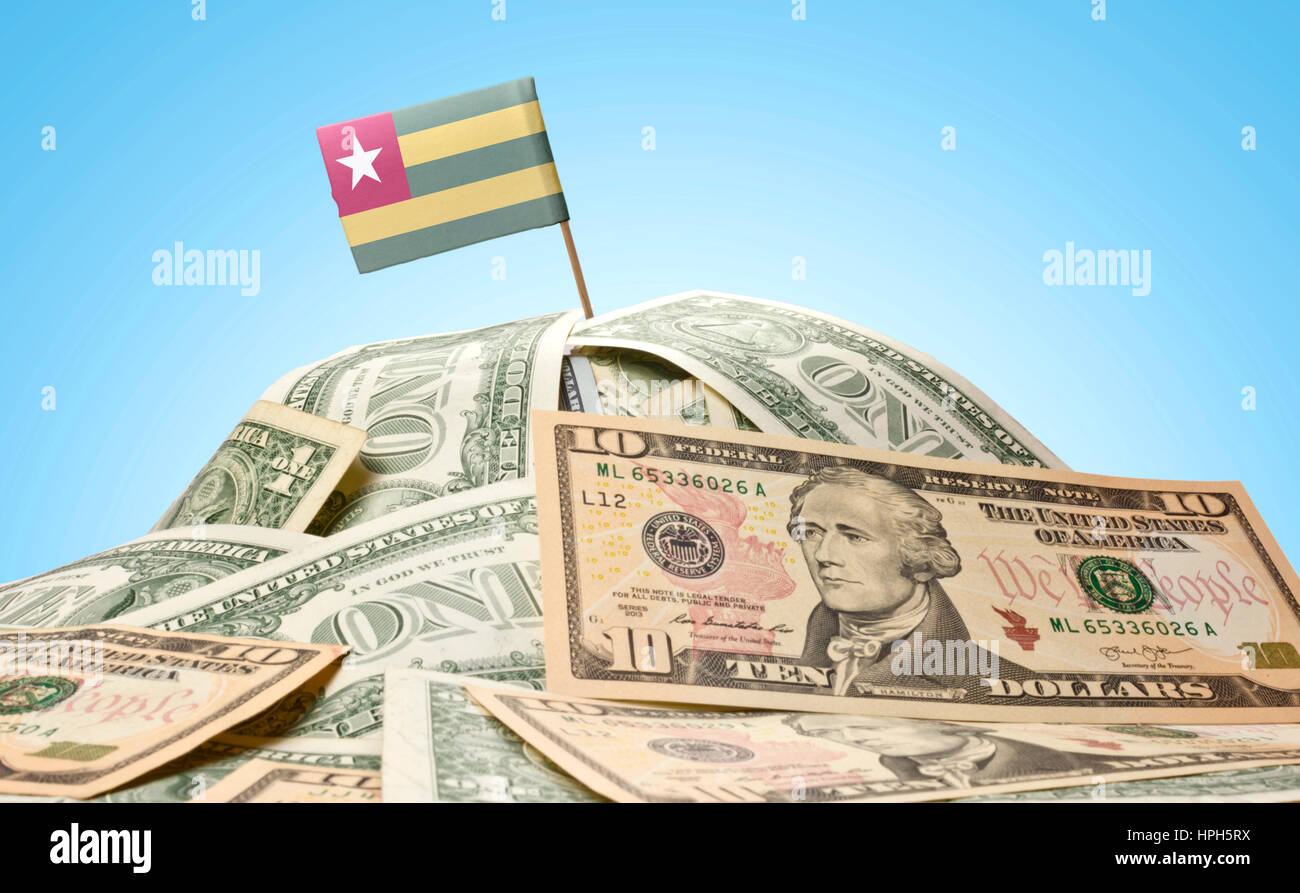 The national flag of Togo sticking in a pile of american dollars