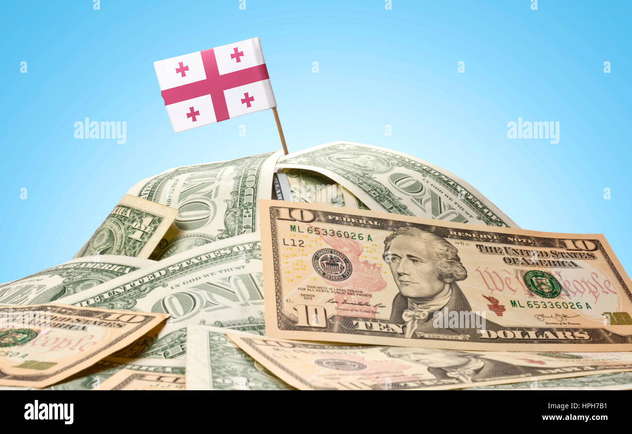 The national flag of Georgia sticking in a pile of american dollars.(series) Stock Photo