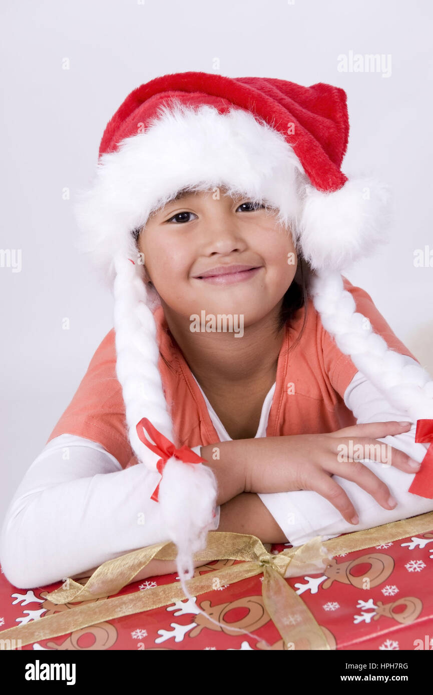 Asiatisches Maedchen mit Weihnachtsgeschenk und Weihnachtsmuetze - girl with christmas present, Model released Stock Photo