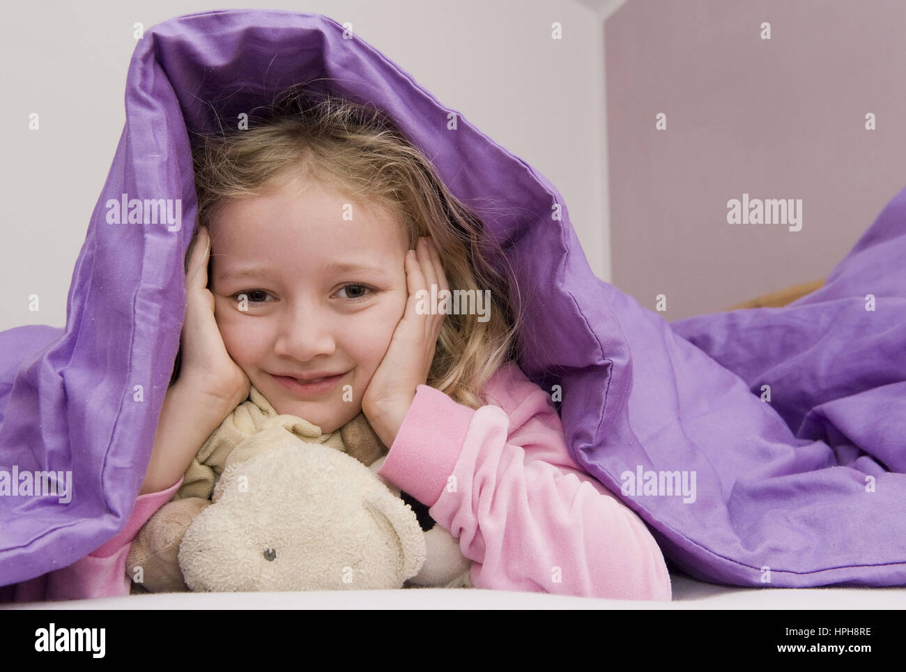 Maedchen liegt unter der Bettdecke - girl lying under bed cover, Model released Stock Photo