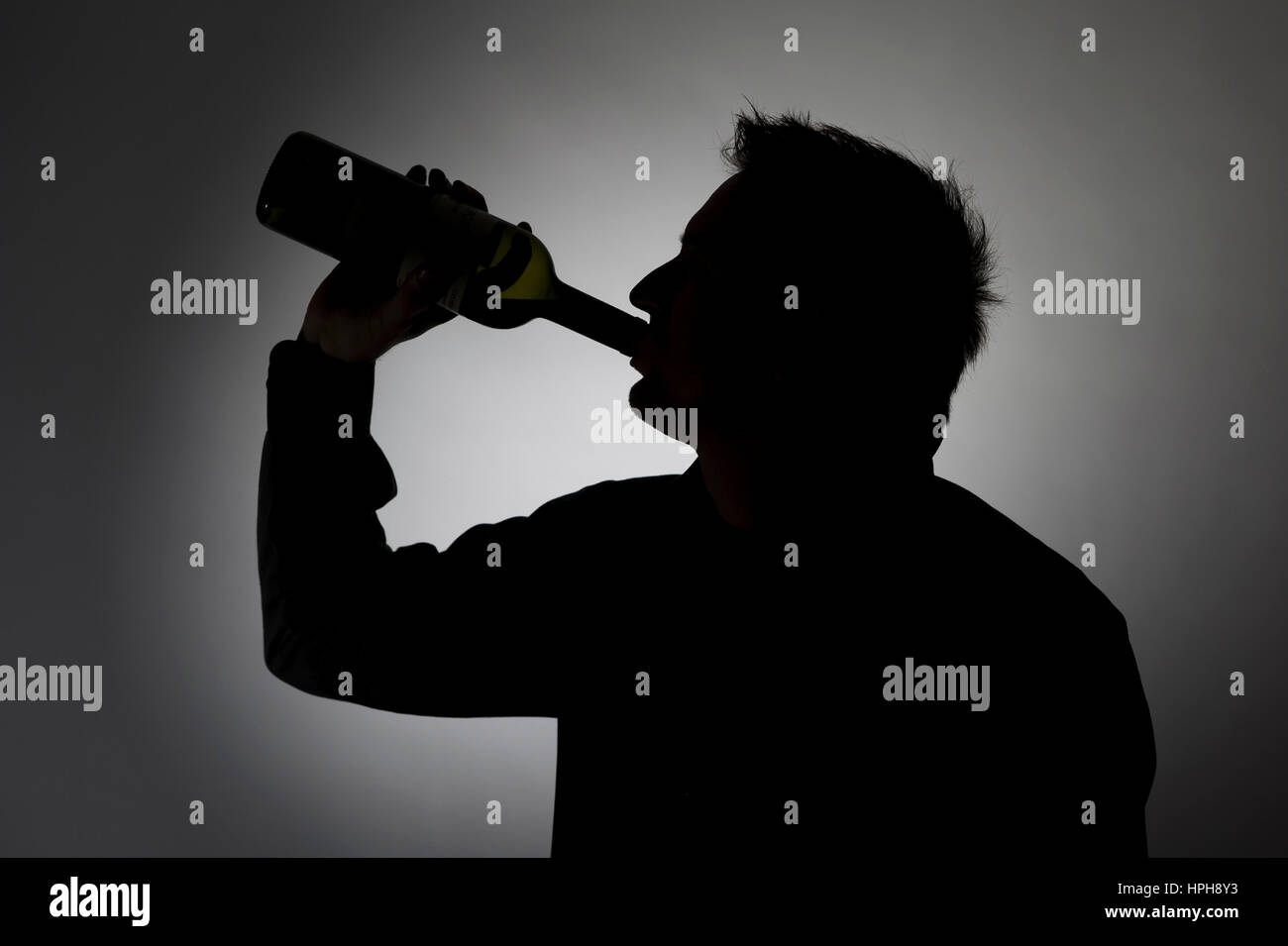 Mann trinkt aus Weinflasche, Silhouette - man drinks a bottle of wine, Model released Stock Photo