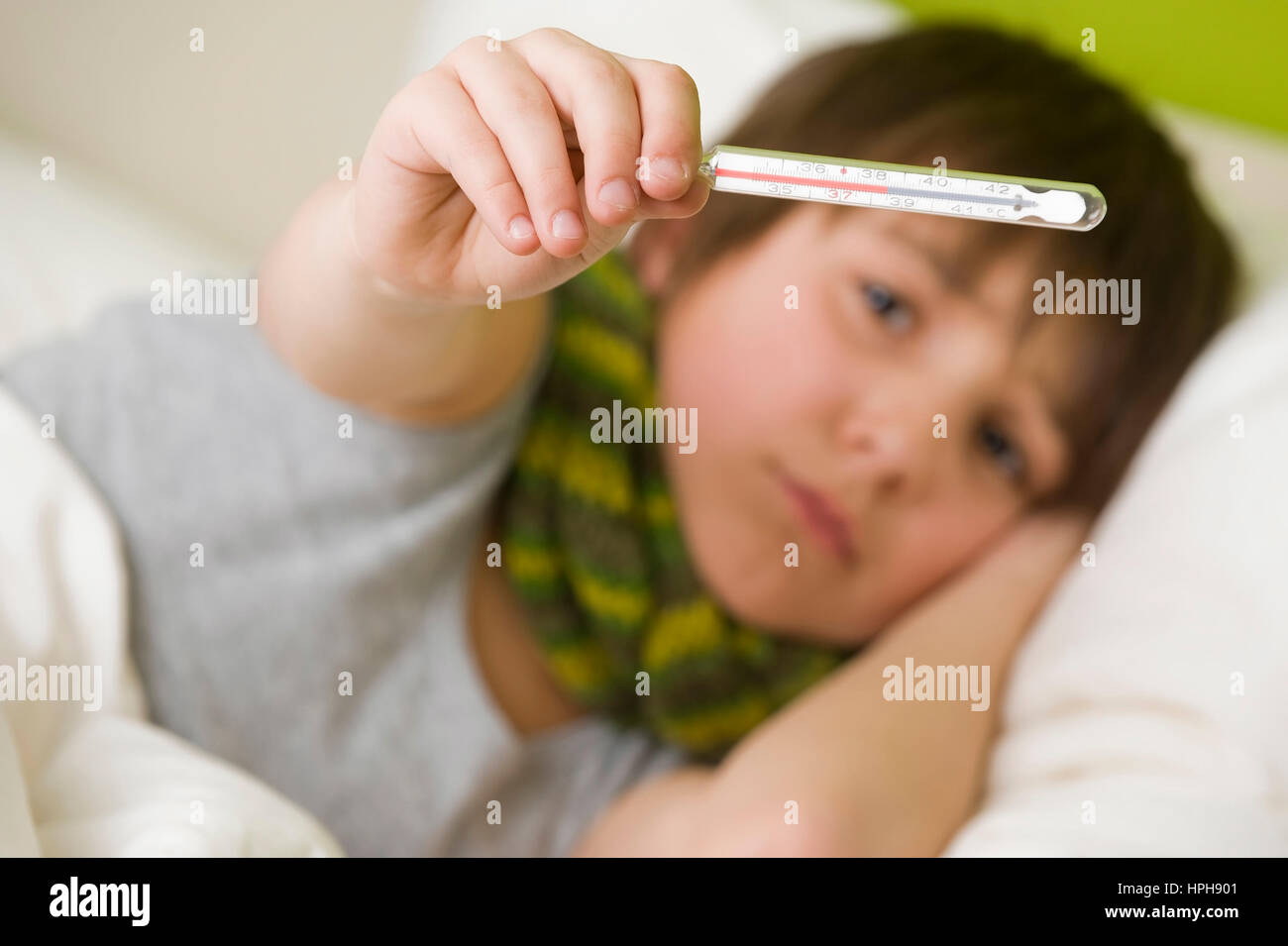 Kranker Junge mit Fieberthermometer im Bett - sick boy with fiver in bed, Model released Stock Photo