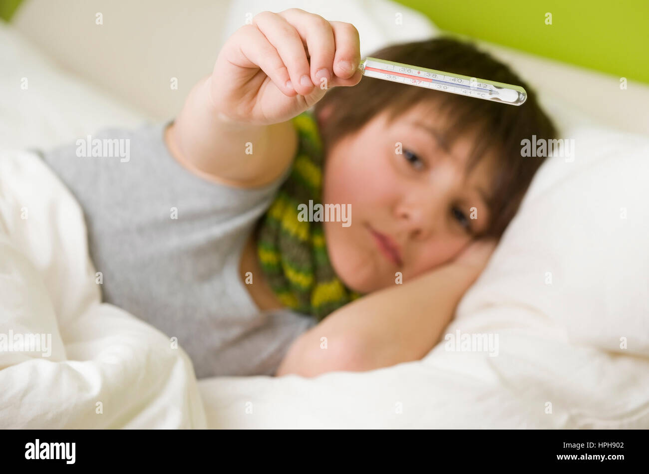 Kranker Junge mit Fieberthermometer im Bett - sick boy with fiver in bed, Model released Stock Photo