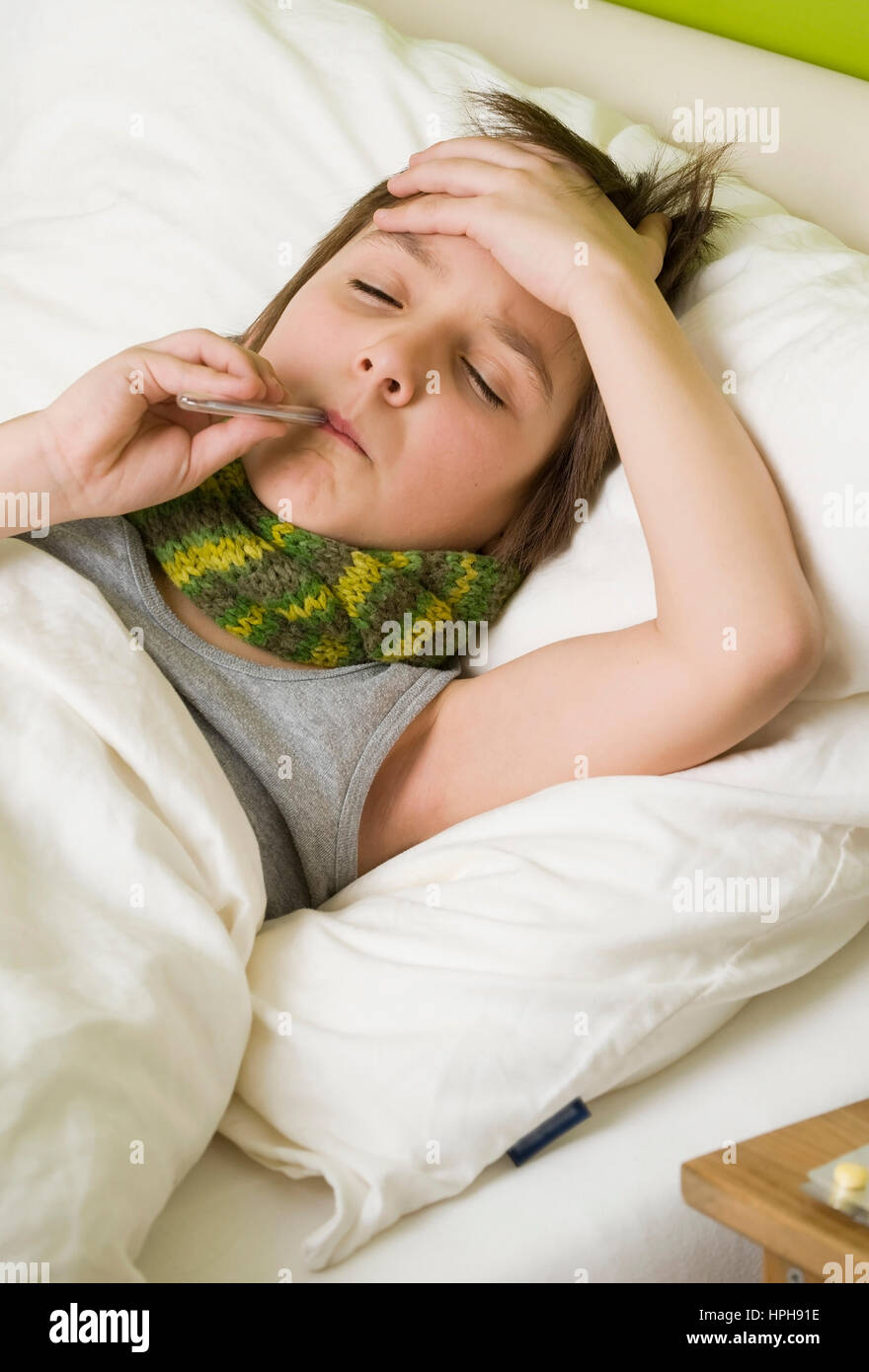 Kranker Junge mit Fieberthermometer im Bett - sick boy with fiver in bed, Model released Stock Photo