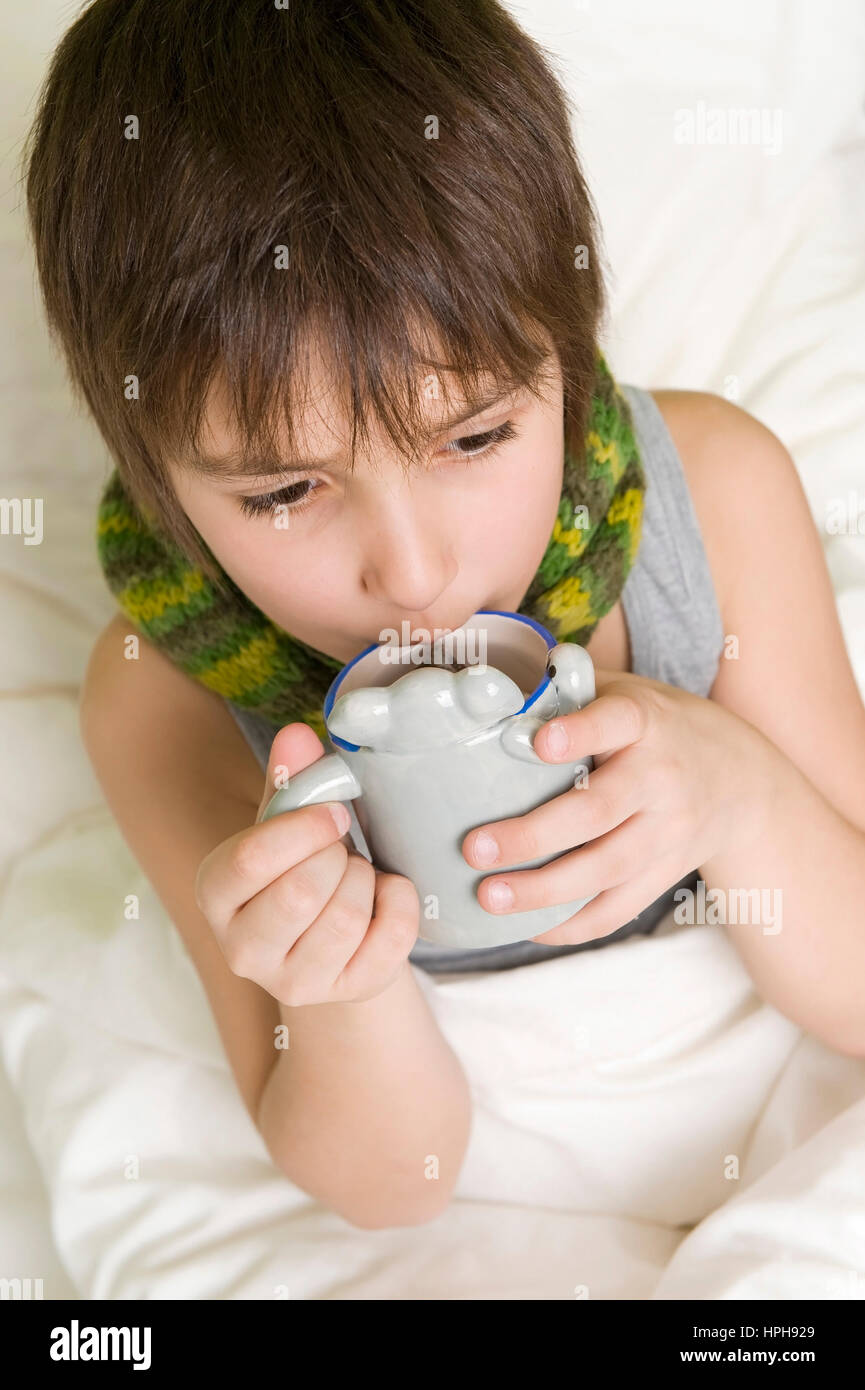 Kranker Junge mit Tasse Tee im Bett - sick boy with cup of tea in bed, Model released Stock Photo