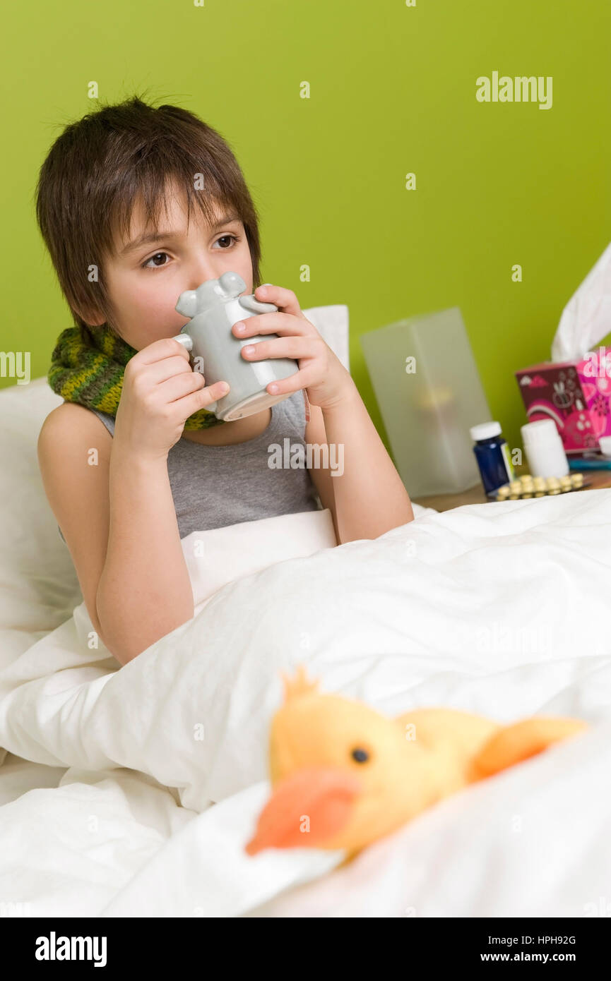 Kranker Junge mit Tasse Tee im Bett - sick boy with cup of tea in bed, Model released Stock Photo