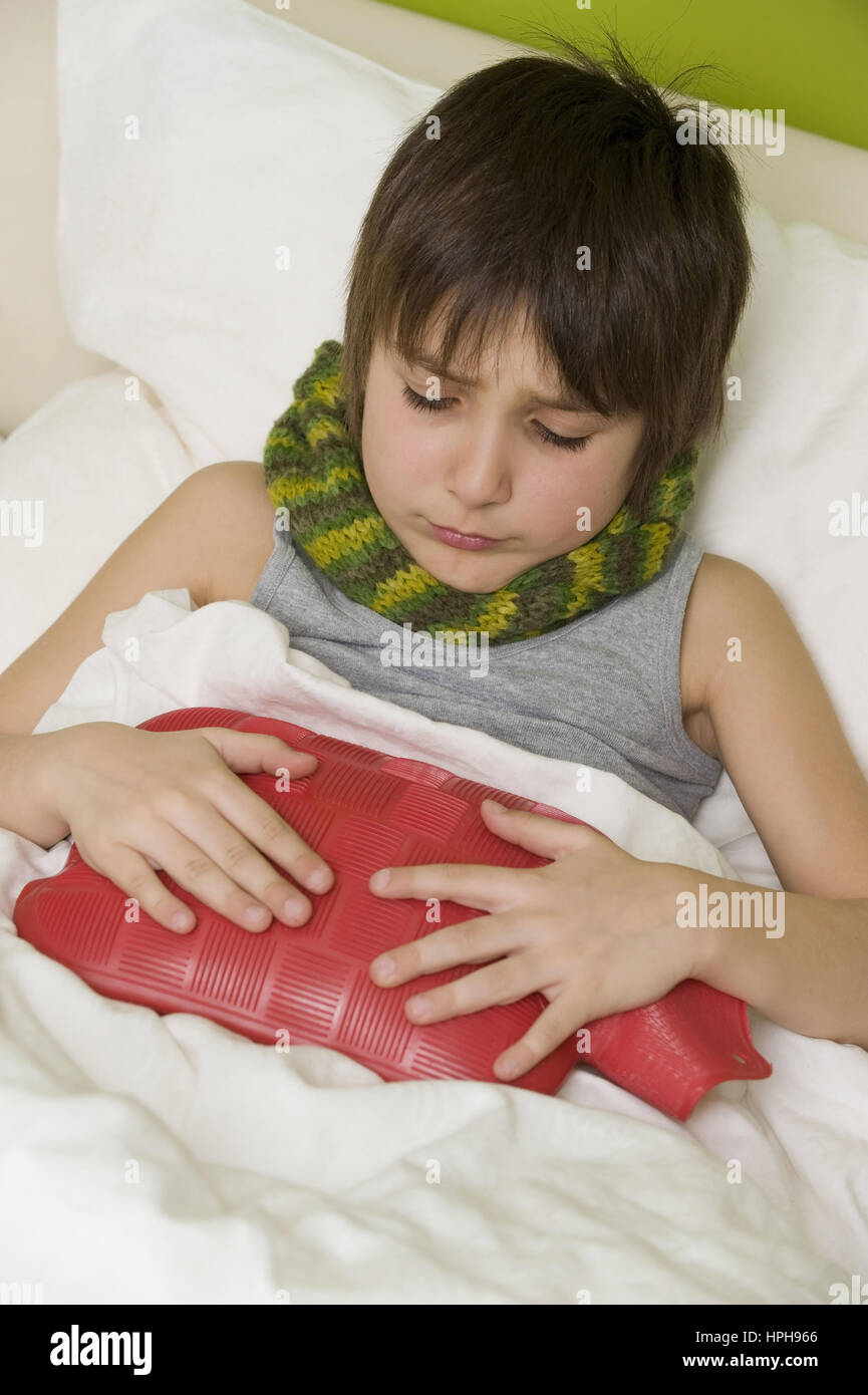 Kranker Junge mit Waermeflasche im Bett - sick boy with hot-water bottle in bed, Model released Stock Photo